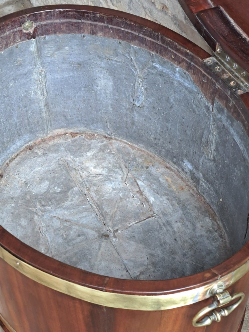 An 18th-century George III oval mahogany cellarette bound with brass straps and supported by four tapered legs. View VII