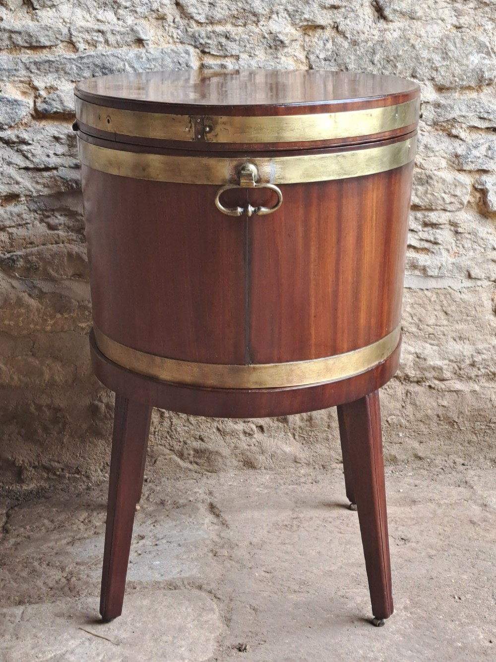 An 18th-century George III oval mahogany cellarette bound with brass straps and supported by four tapered legs. View VIII