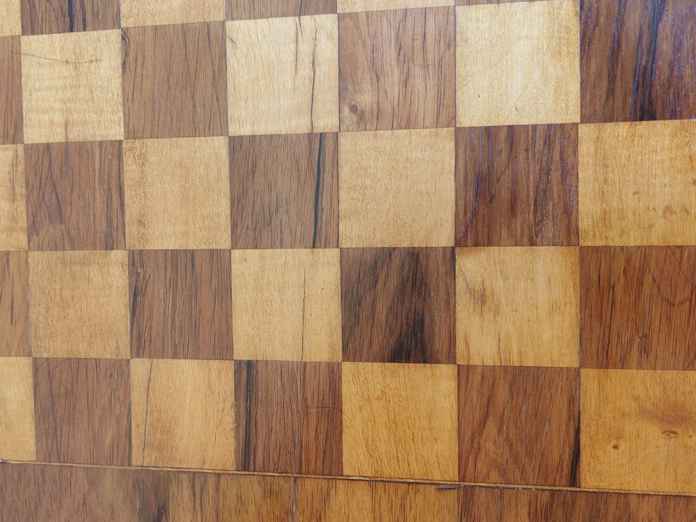 An oval walnut occasional table featuring an inlaid square chess board in the centre, supported by turned legs and a stretcher base. View VI