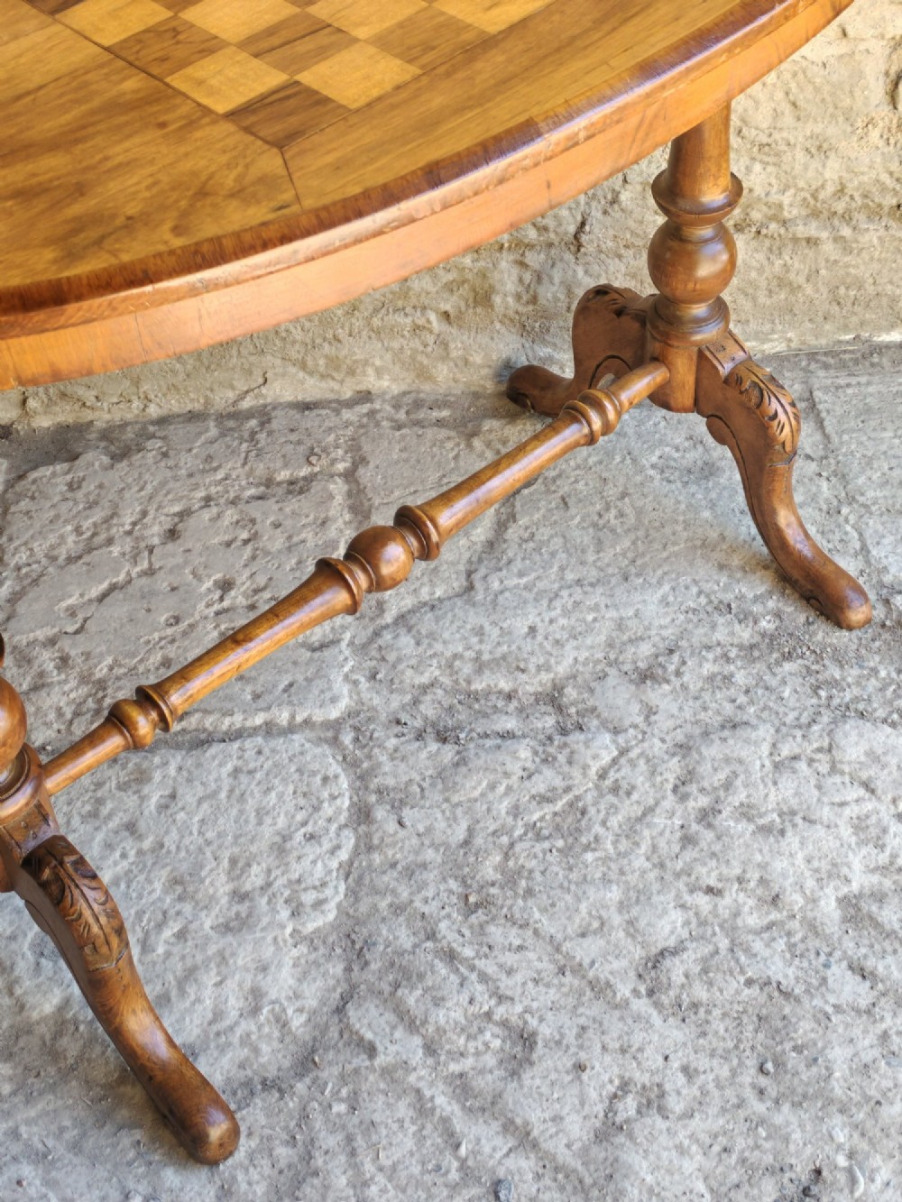 An oval walnut occasional table featuring an inlaid square chess board in the centre, supported by turned legs and a stretcher base. View VII