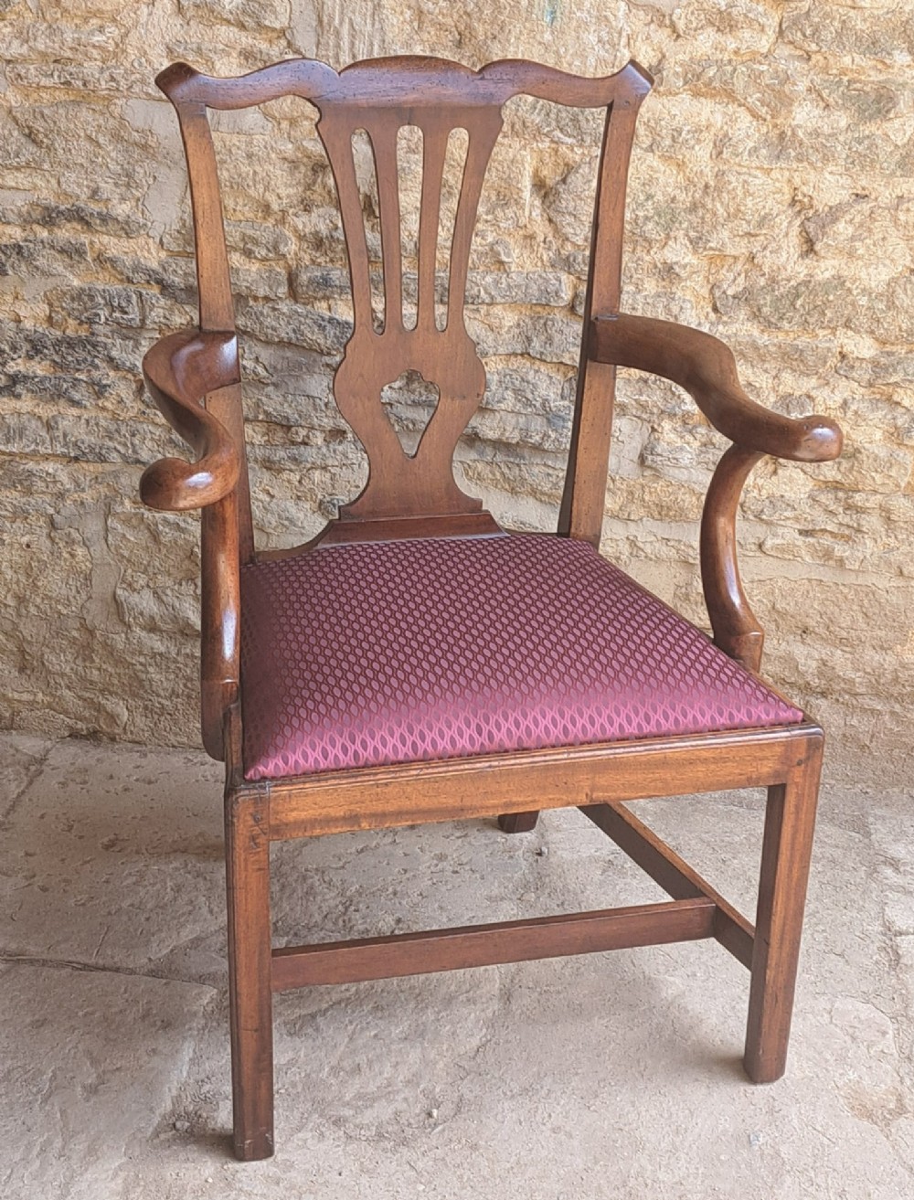 An 18th-century Irish walnut open armchair featuring a carved pierced splat, shaped armrests, an H-stretcher base, and a burgundy pattern upholstered seat. View II