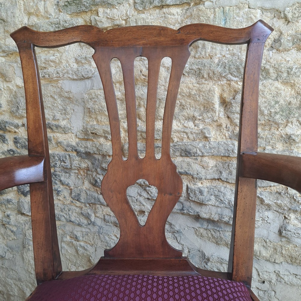 An 18th-century Irish walnut open armchair featuring a carved pierced splat, shaped armrests, an H-stretcher base, and a burgundy pattern upholstered seat. View IV
