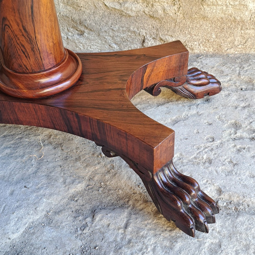 An antique rosewood drop-leaf sewing table with a central drawer, a suspended patterned fabric basket, a turned pedestal column, and carved claw feet. View VI