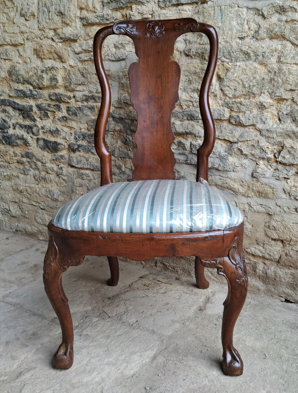 An 18th-century red walnut side chair with a shaped splat back, striped upholstered seat, and carved cabriole legs.