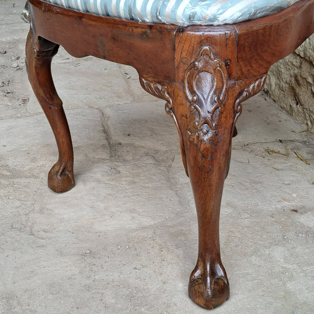 An 18th-century red walnut side chair with a shaped splat back, striped upholstered seat, and carved cabriole legs. View VI