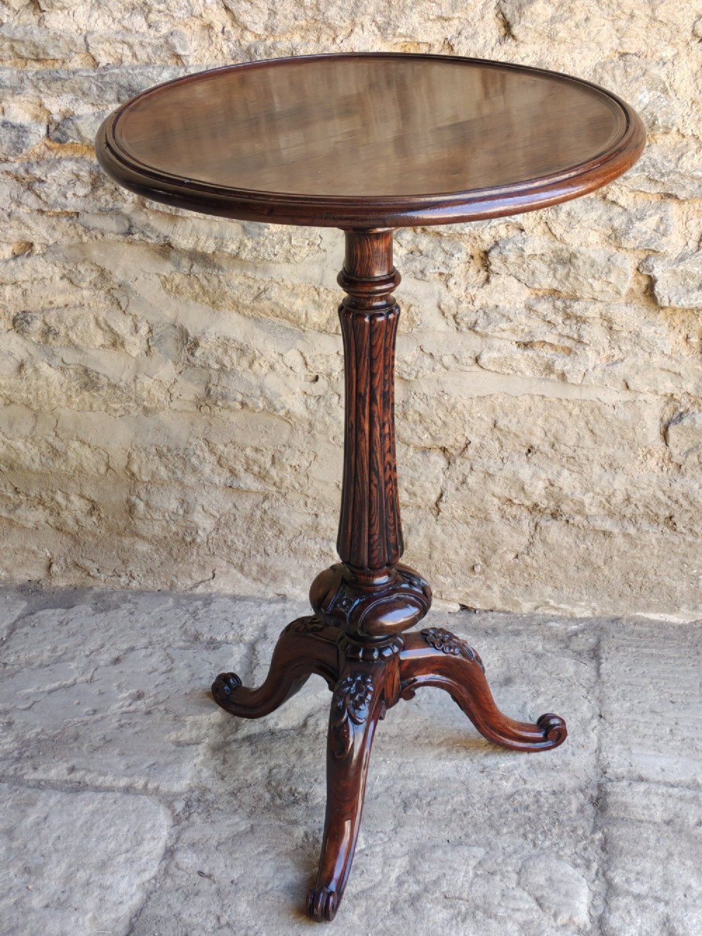 A circular dark rosewood Regency occasional table featuring a turned pedestal column and carved tripod legs.