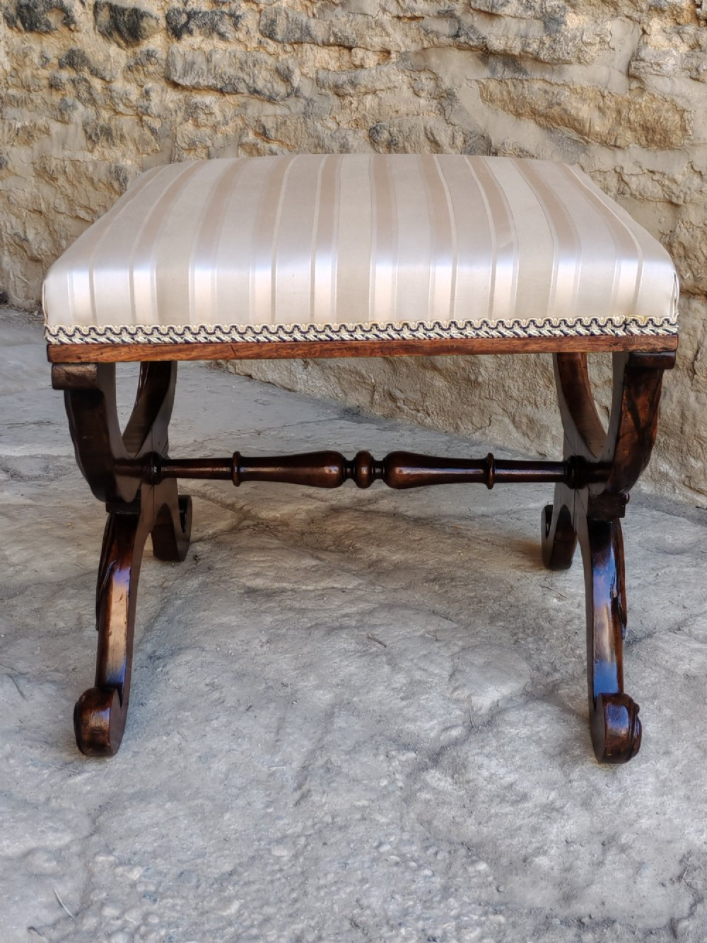 A Regency rosewood X-frame stool featuring intricately carved acanthus leaf scroll legs, a turned central stretcher, and a striped upholstered seat. View III