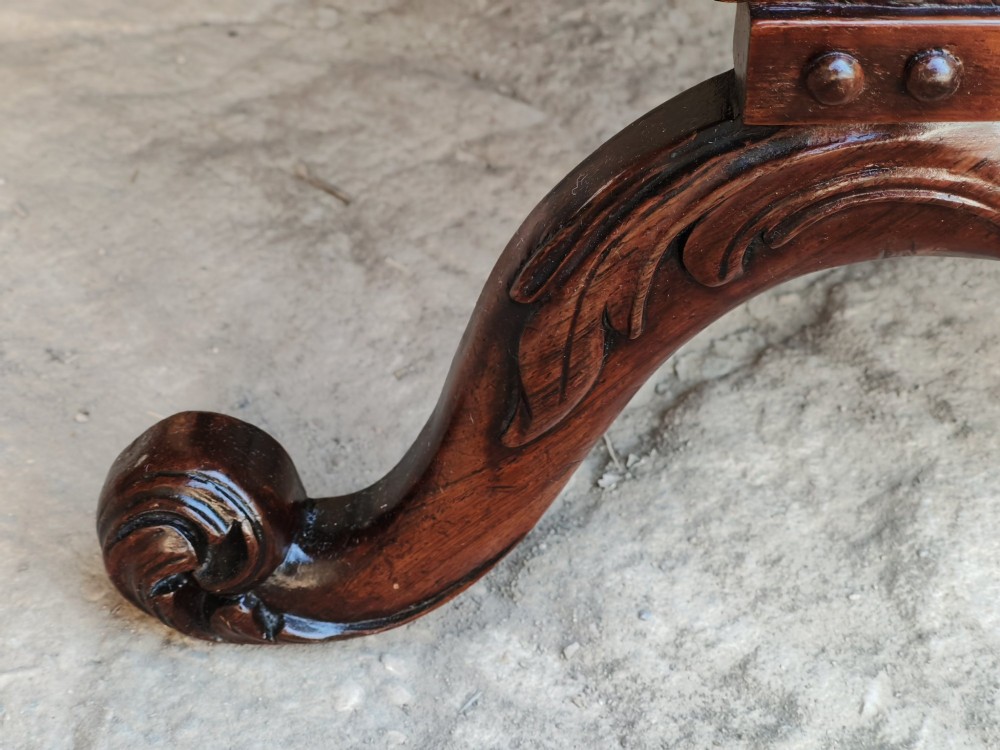 A Regency rosewood X-frame stool featuring intricately carved acanthus leaf scroll legs, a turned central stretcher, and a striped upholstered seat. View VI