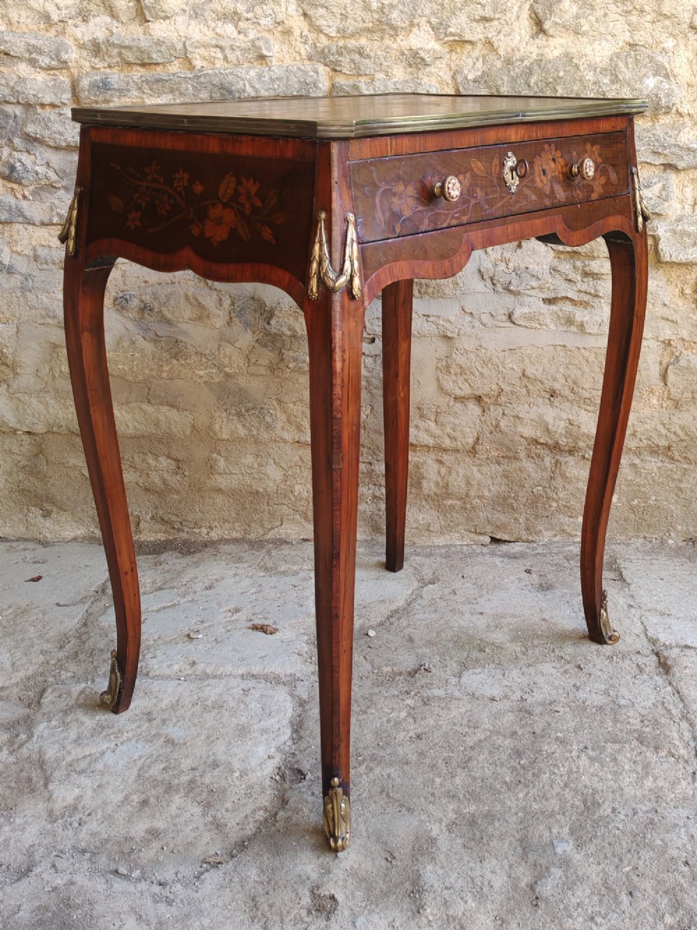 An 18th-century Dutch marquetry side table featuring a pictorial inlaid tabletop depicting a landscape, a floral drawer front, cabriole legs, and brass mounts. View II