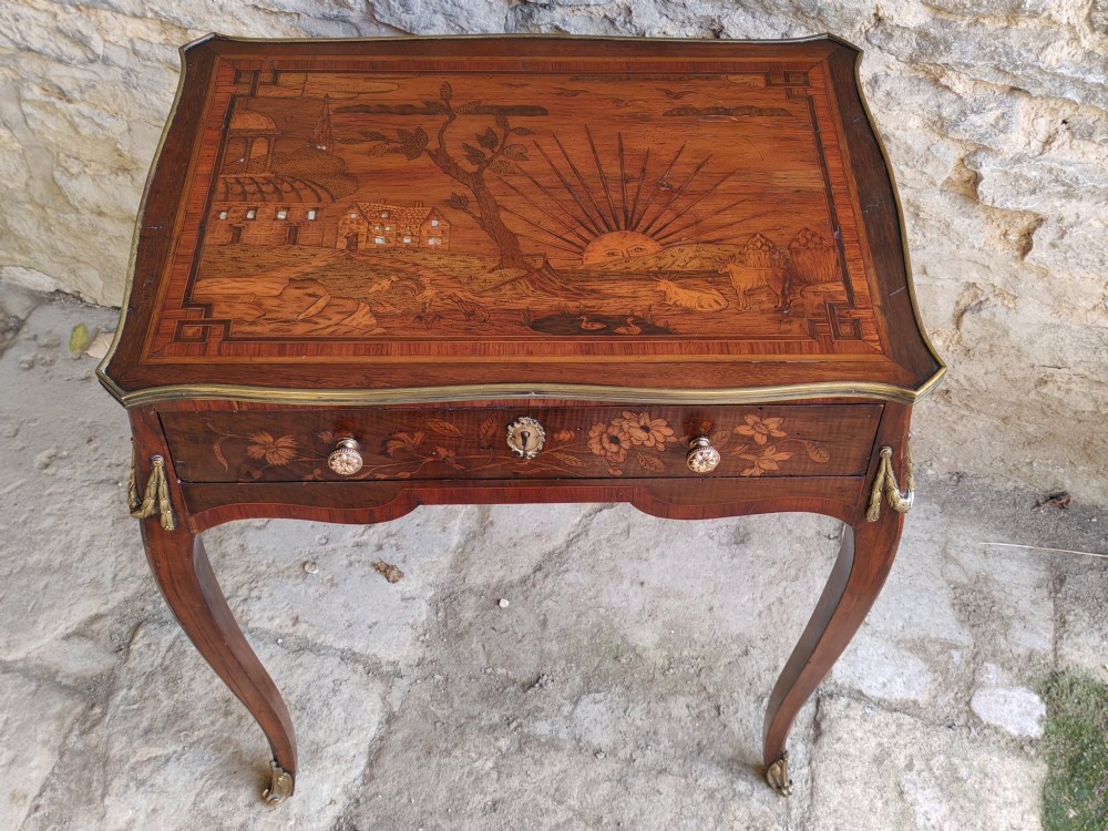 An 18th-century Dutch marquetry side table featuring a pictorial inlaid tabletop depicting a landscape, a floral drawer front, cabriole legs, and brass mounts. View III