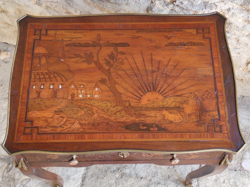 An 18th-century Dutch marquetry side table featuring a pictorial inlaid tabletop depicting a landscape, a floral drawer front, cabriole legs, and brass mounts. View IV
