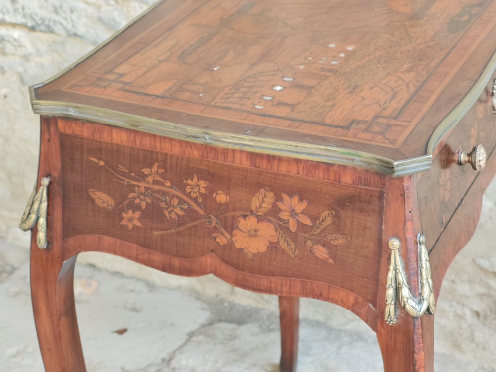 An 18th-century Dutch marquetry side table featuring a pictorial inlaid tabletop depicting a landscape, a floral drawer front, cabriole legs, and brass mounts. View V