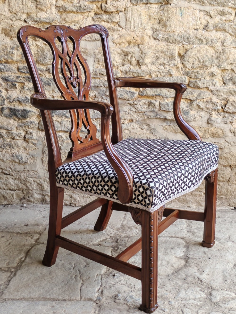 A Georgian mahogany carver armchair featuring a pierced back splat, shaped arms, square carved front legs, and geometric patterned fabric seating. View II