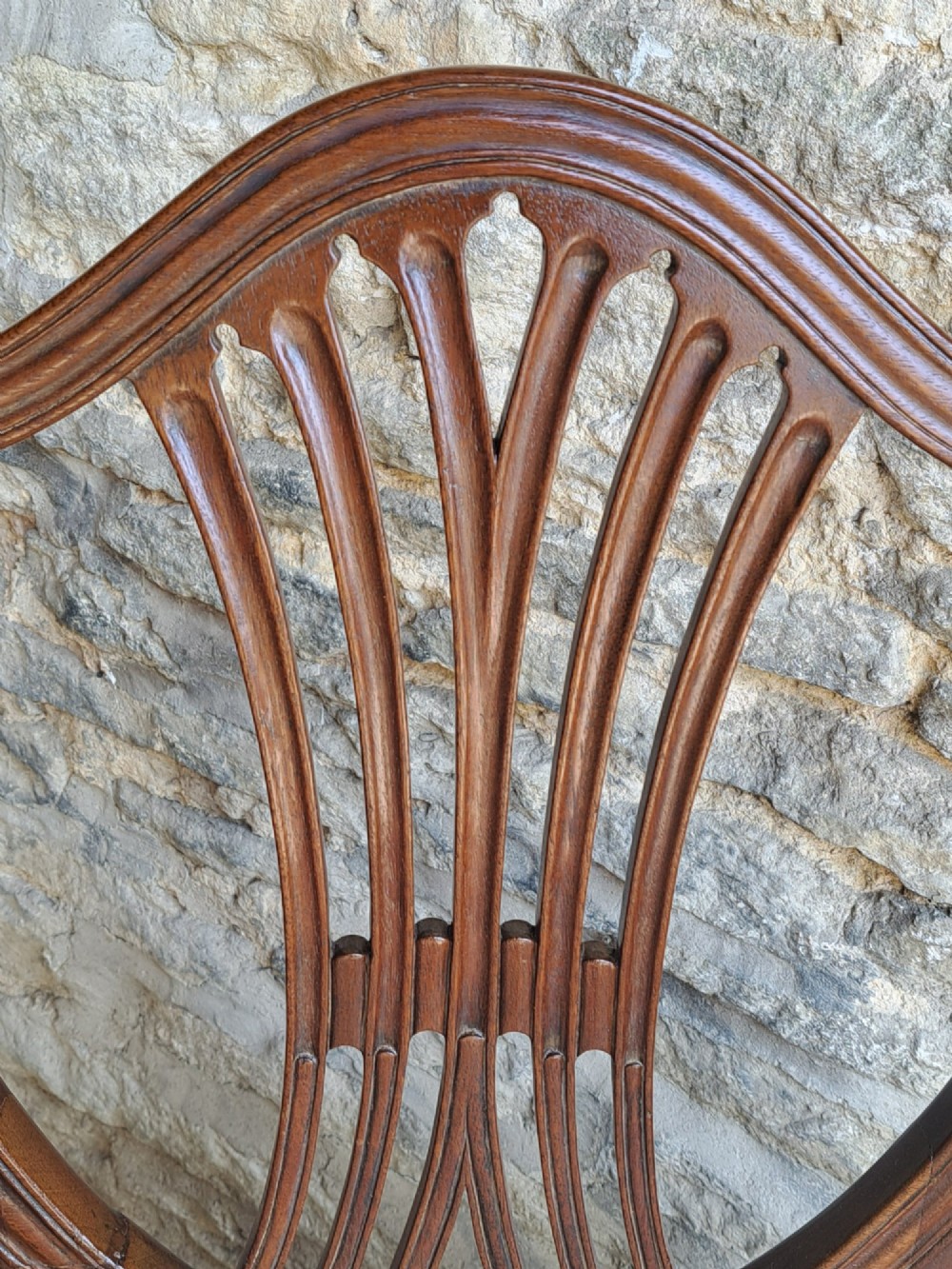 A pair of late 18th-century mahogany Hepplewhite dining chairs featuring carved shield backs and cream leather seats with brass stud detailing. View V