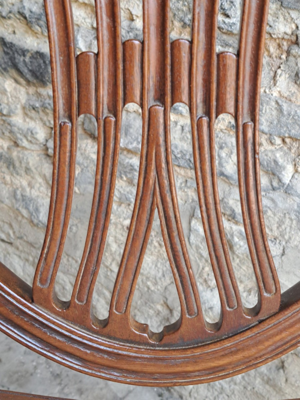 A pair of late 18th-century mahogany Hepplewhite dining chairs featuring carved shield backs and cream leather seats with brass stud detailing. View VI
