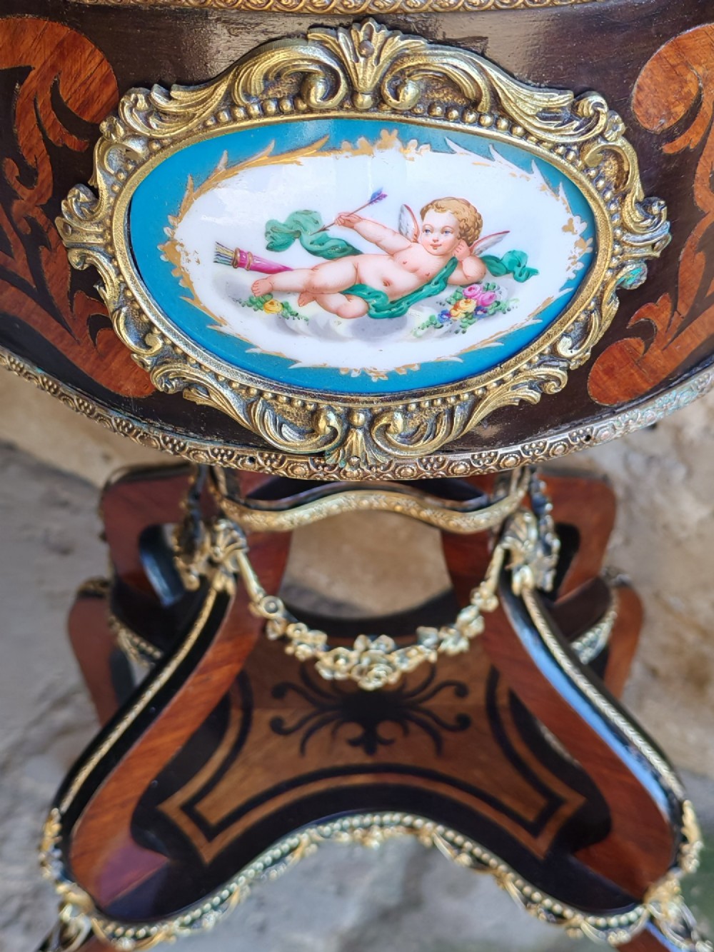 A 19th-century French marquetry jardiniere table with intricate wood inlay, ornate gilded mounts, a cherub porcelain plaque, and cabriole legs. View III