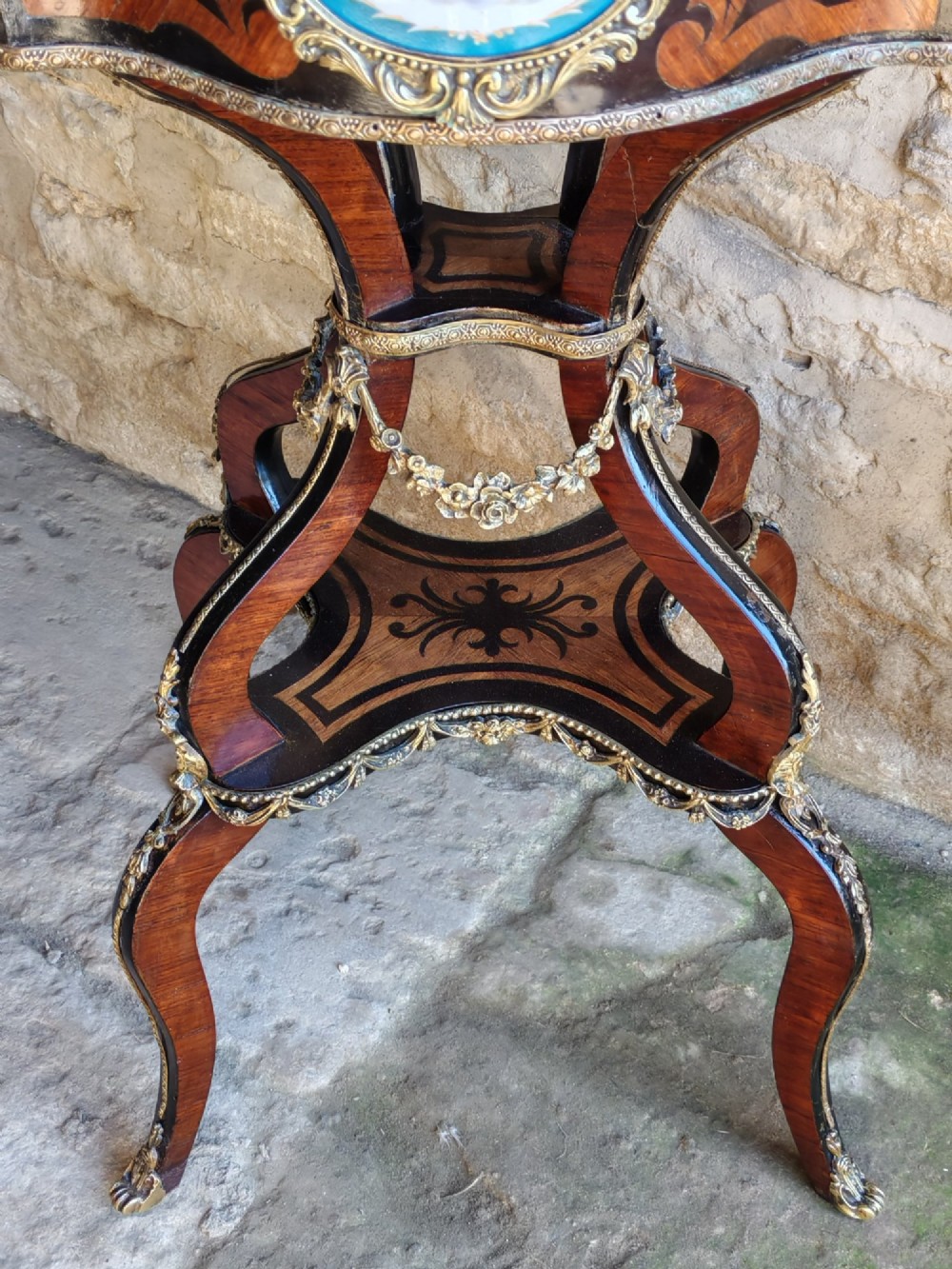 A 19th-century French marquetry jardiniere table with intricate wood inlay, ornate gilded mounts, a cherub porcelain plaque, and cabriole legs. View V