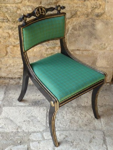 A set of four ebonised and parcel-gilt Regency side chairs featuring curved sabre legs, carved top rails, and vibrant green upholstered seats. View II
