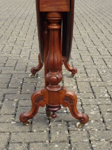 A Victorian solid walnut Sutherland table with folded drop leaves, turned baluster supports, and ceramic castors. View VI
