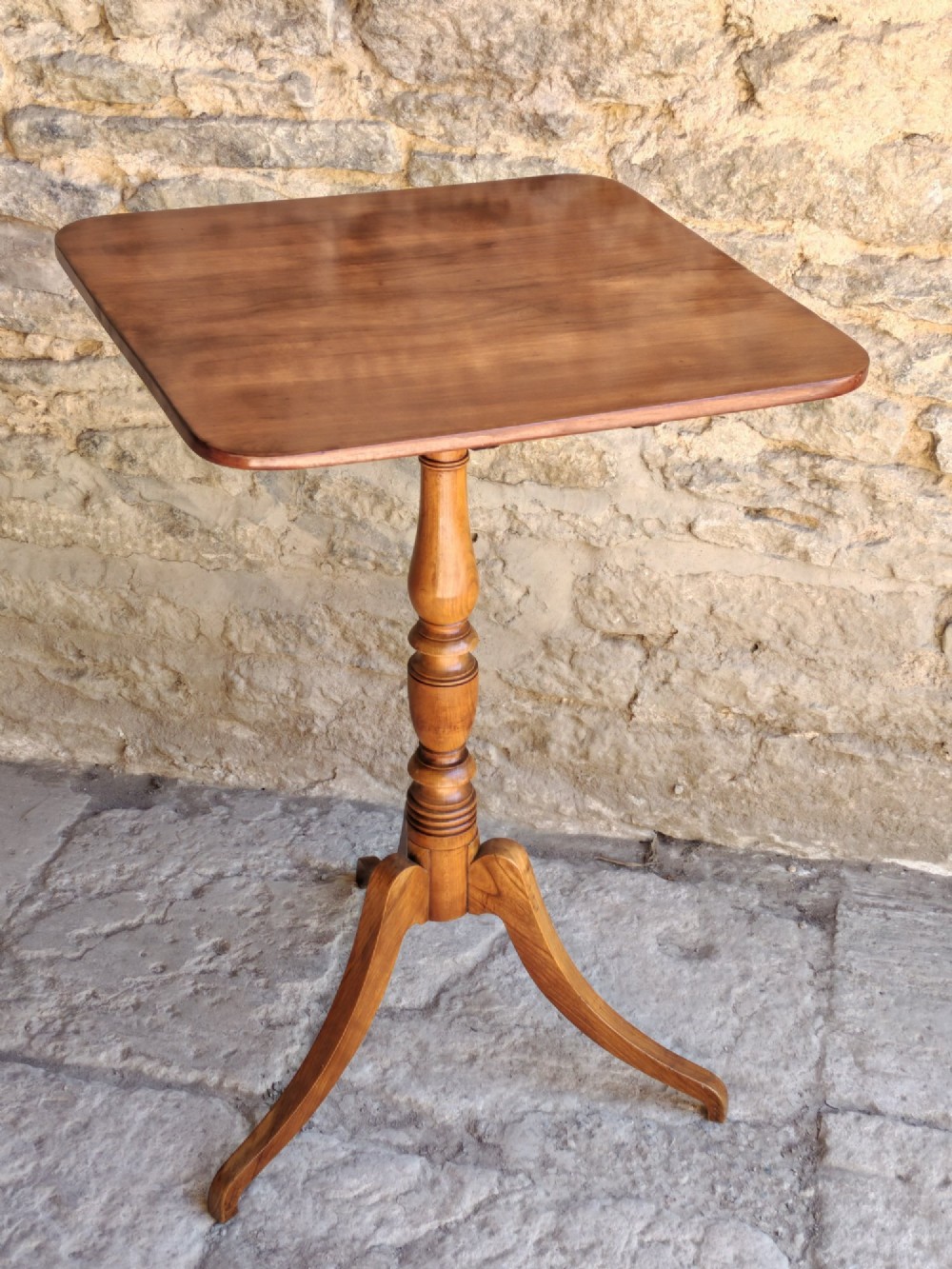 A square top antique fruitwood wine table featuring rounded corners, a central turned baluster stem, and three splayed tripod legs. View II