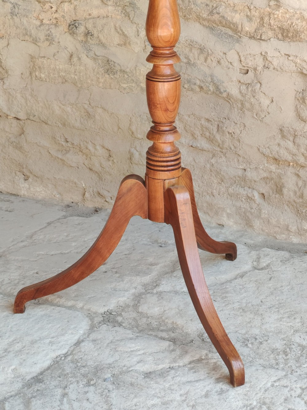 A square top antique fruitwood wine table featuring rounded corners, a central turned baluster stem, and three splayed tripod legs. View VI