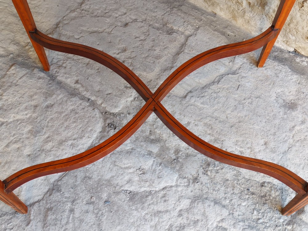 A late Victorian satinwood bijouterie table featuring an oval glazed top aperture, glass side panels, tapered square legs, and an X-form stretcher. View VIII