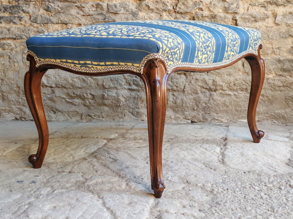 An antique walnut stool featuring carved cabriole legs and a patterned blue and yellow striped upholstered top with gimp trim. View III