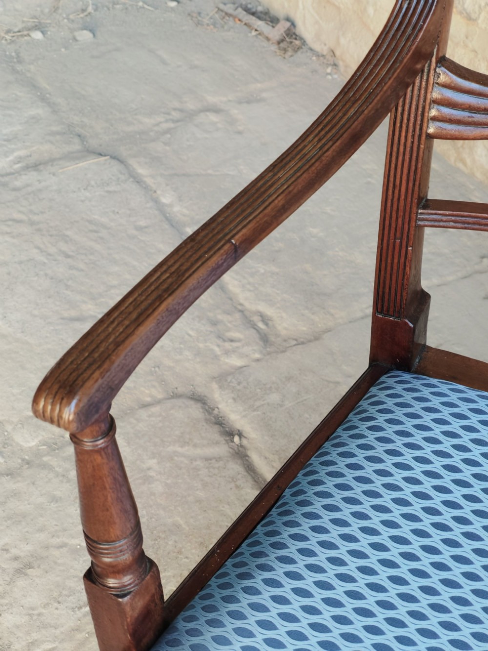 A late Georgian mahogany carver chair featuring carved reeded back rails, curved armrests, and a blue patterned drop-in seat. View IV
