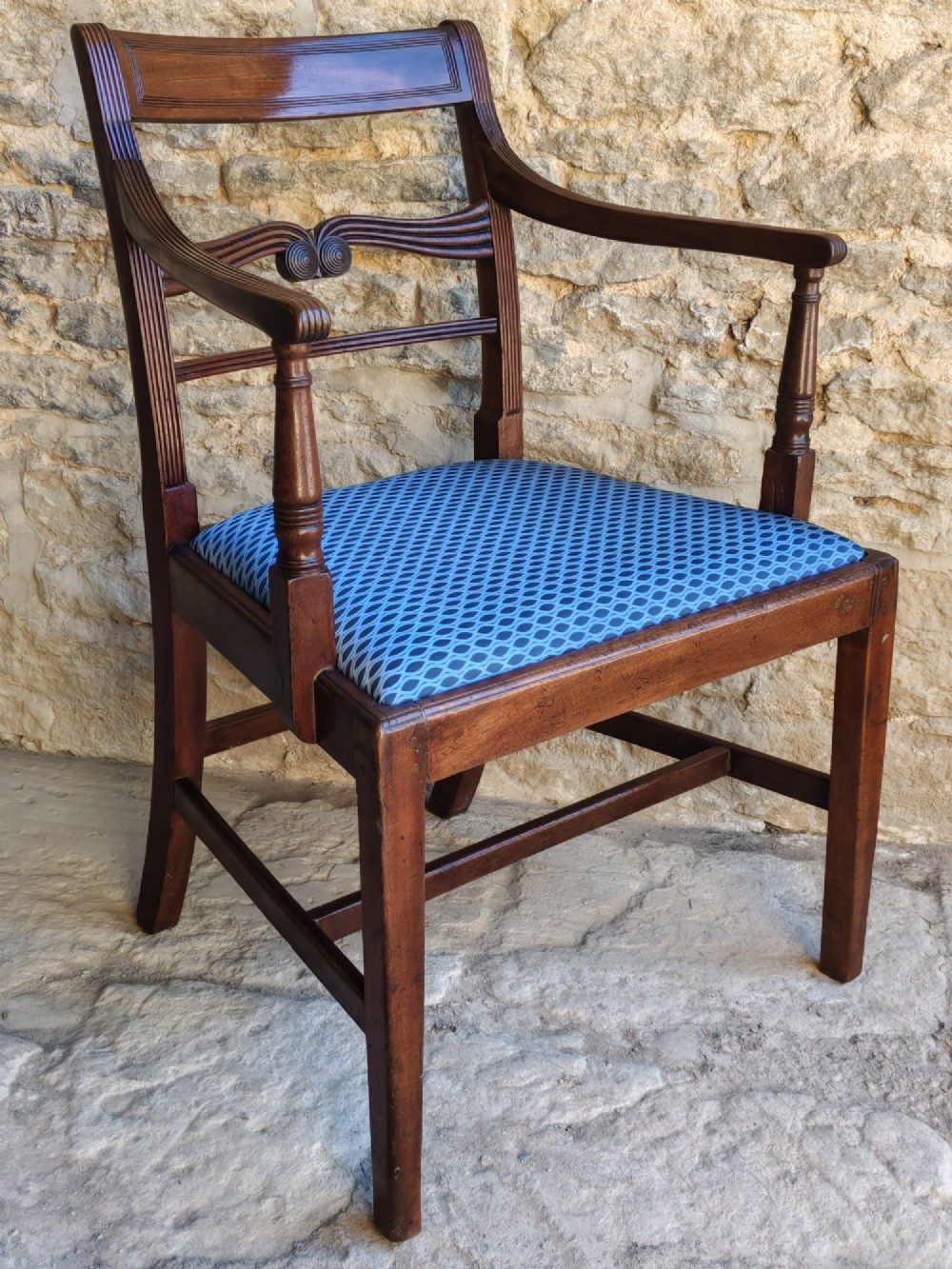 A late Georgian mahogany carver chair featuring carved reeded back rails, curved armrests, and a blue patterned drop-in seat. View V