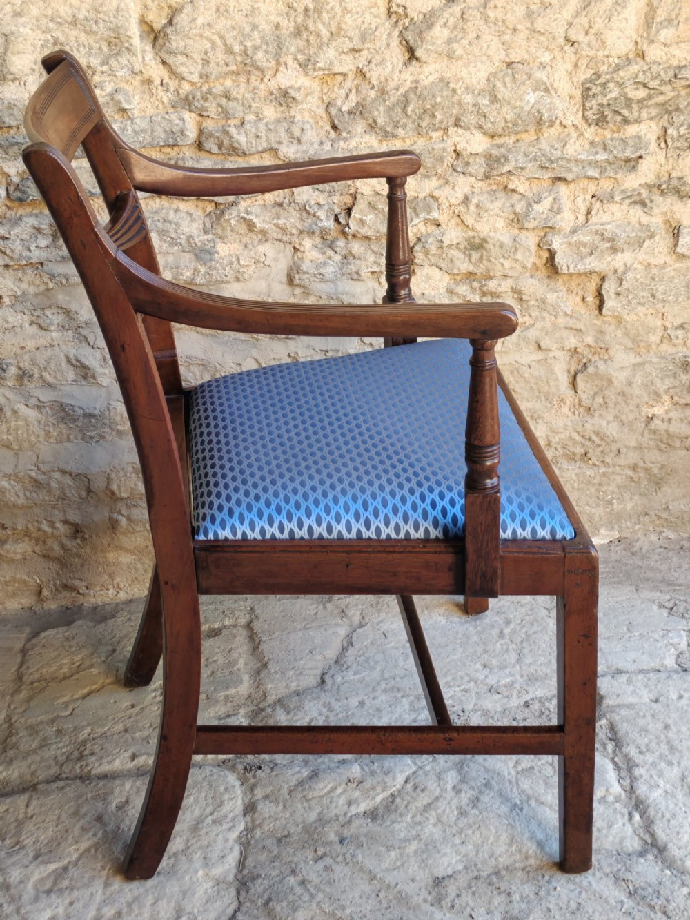 A late Georgian mahogany carver chair featuring carved reeded back rails, curved armrests, and a blue patterned drop-in seat. View VI