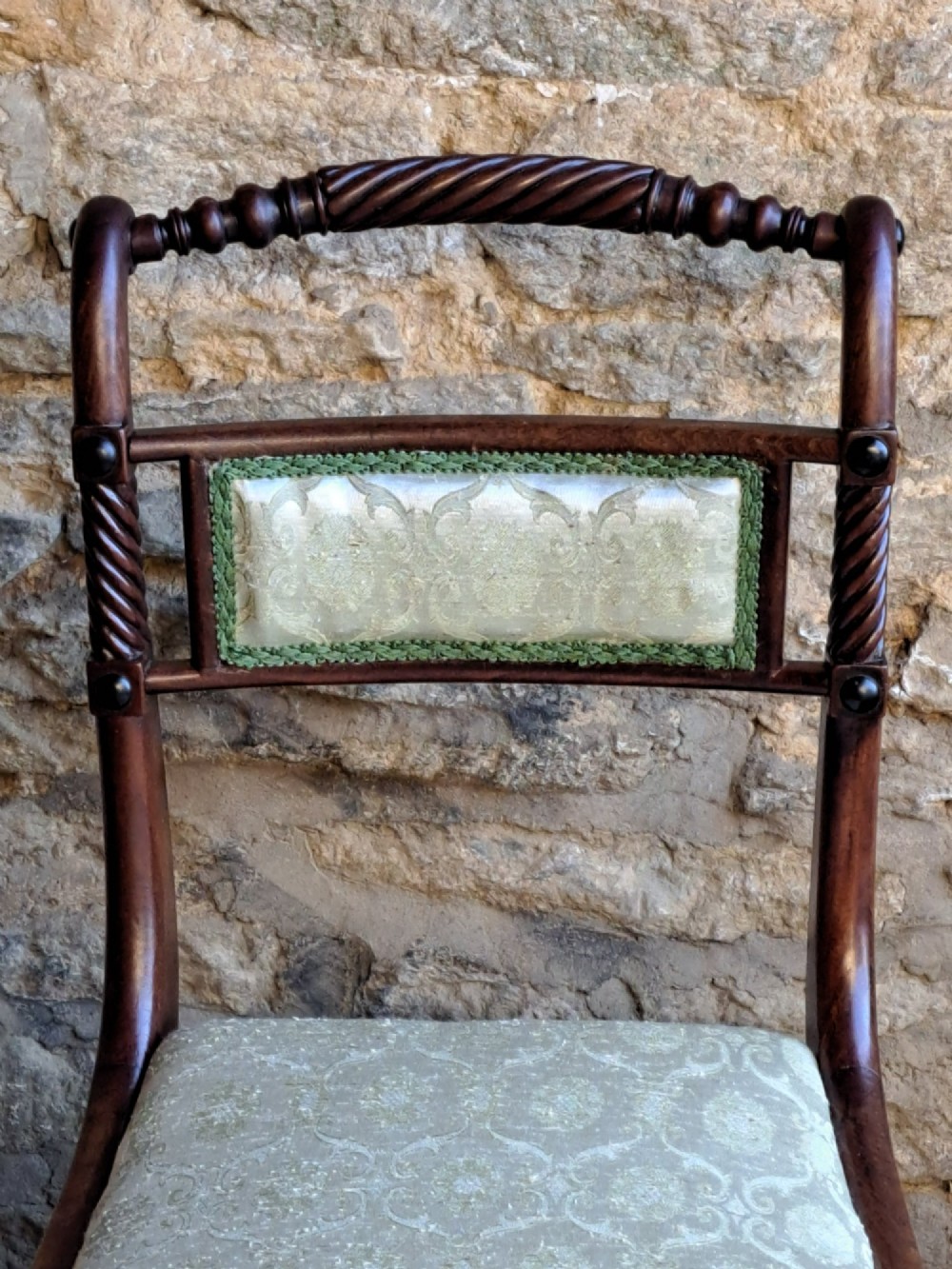 A set of ten 19th-century rosewood dining chairs featuring carved rope-twist top rails, curved sabre legs, and pale green upholstered seats. View V
