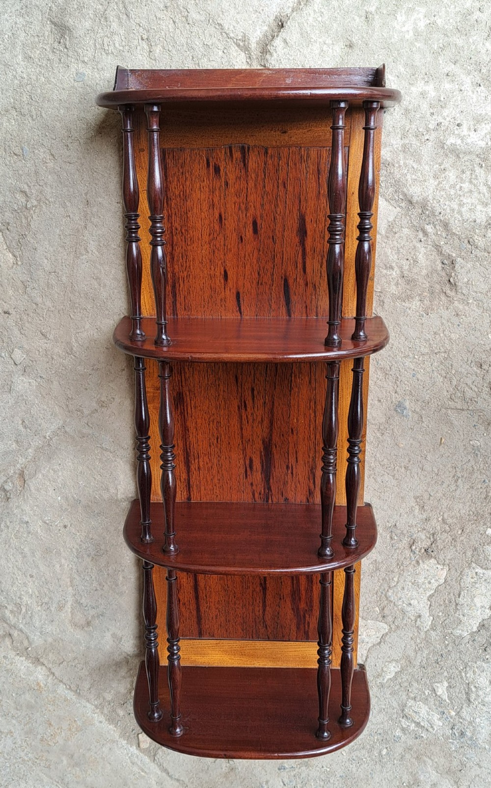 A four-tiered mahogany hanging wall shelf with turned spindle supports and a solid timber backboard. View VI