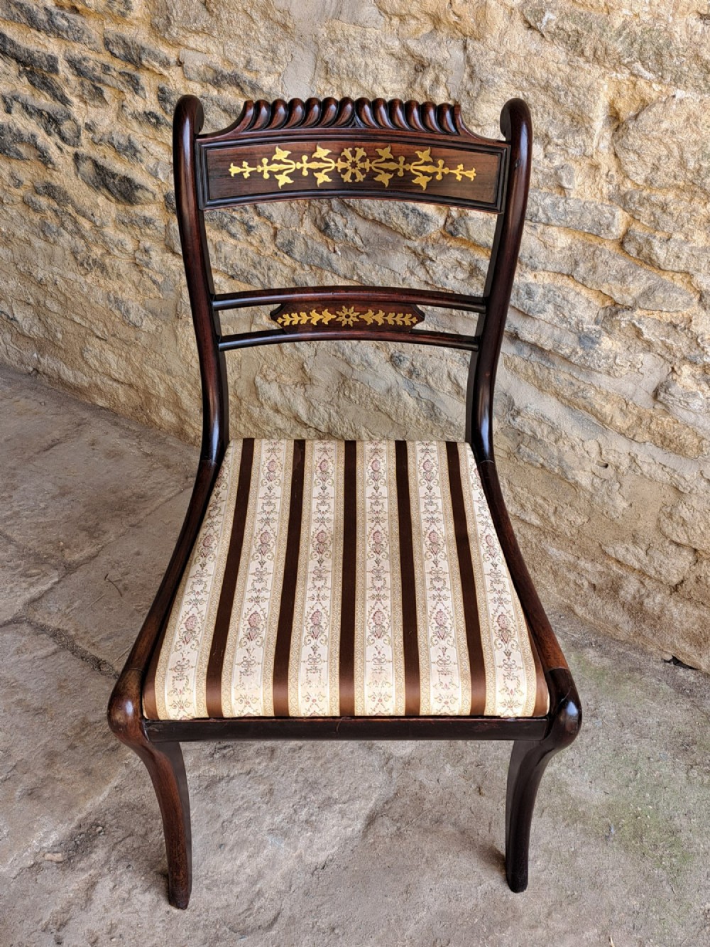 A set of four dark rosewood Regency dining chairs featuring intricate brass inlaid backrails, carved crests, hand-woven cane seats, and curved sabre legs. View VIII