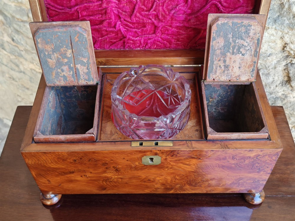 An 18th-century Georgian yew wood tea caddy featuring rich grain figure, a top brass handle, a brass escutcheon, and bun feet. View V