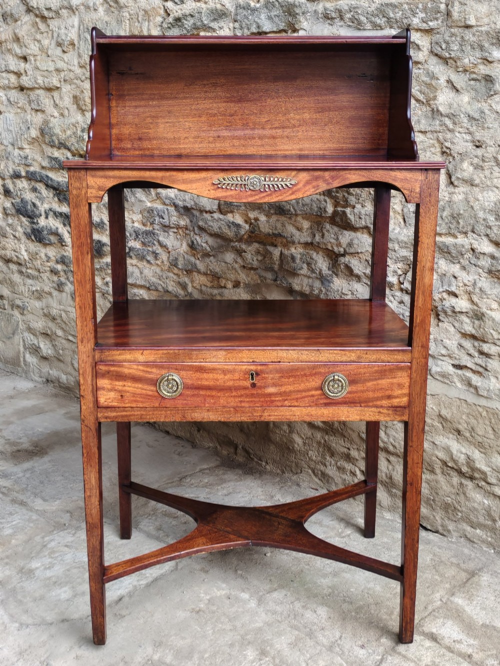 A Georgian mahogany bedside table featuring an upper shelf gallery, a middle tier, a single drawer with brass ring handles, and an X-shaped cross stretcher. View VII