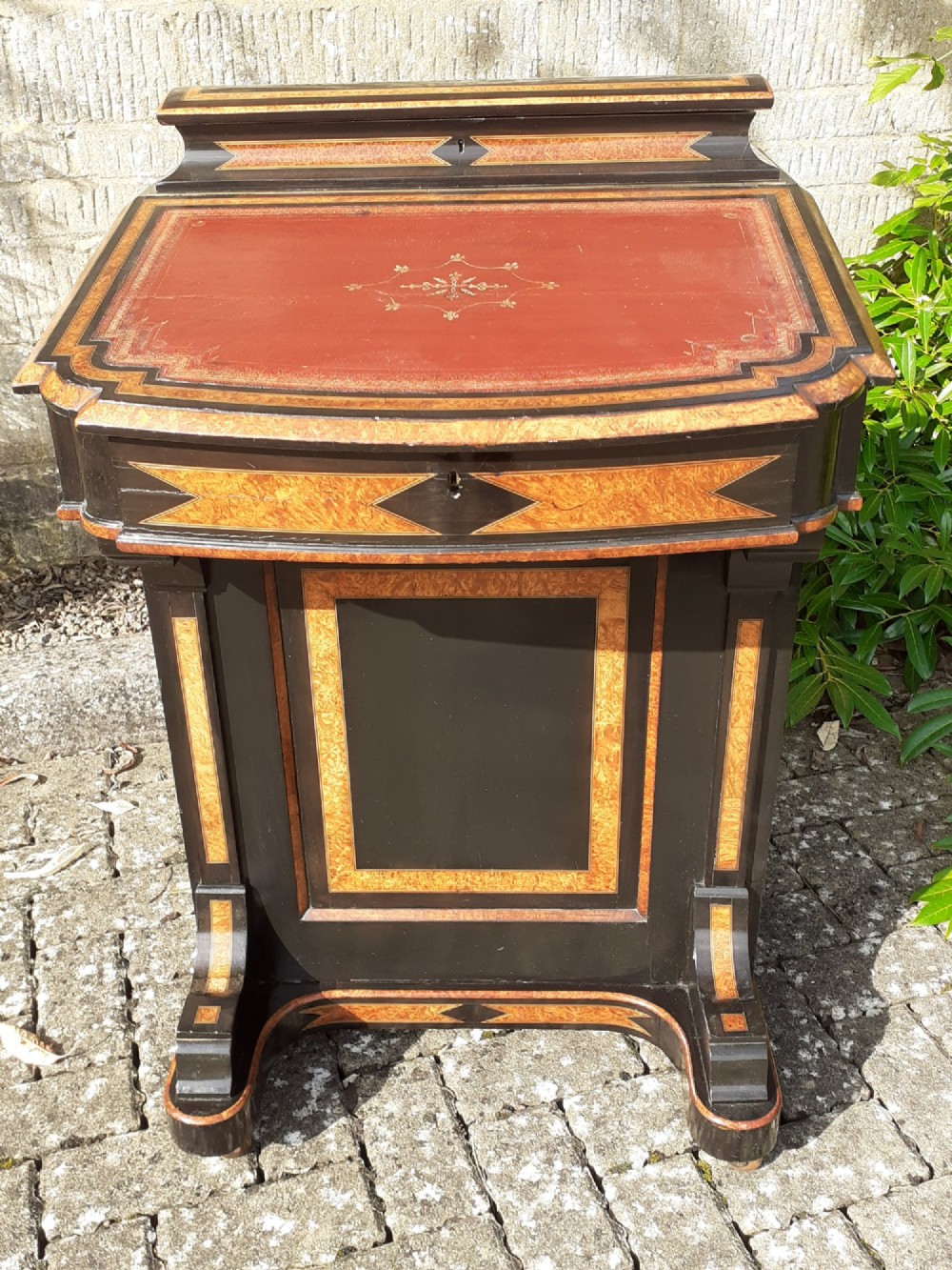 A Victorian ebonised and amboyna Davenport desk featuring a slanted leather-lined writing surface above a side cabinet door opening to reveal internal drawers. View II