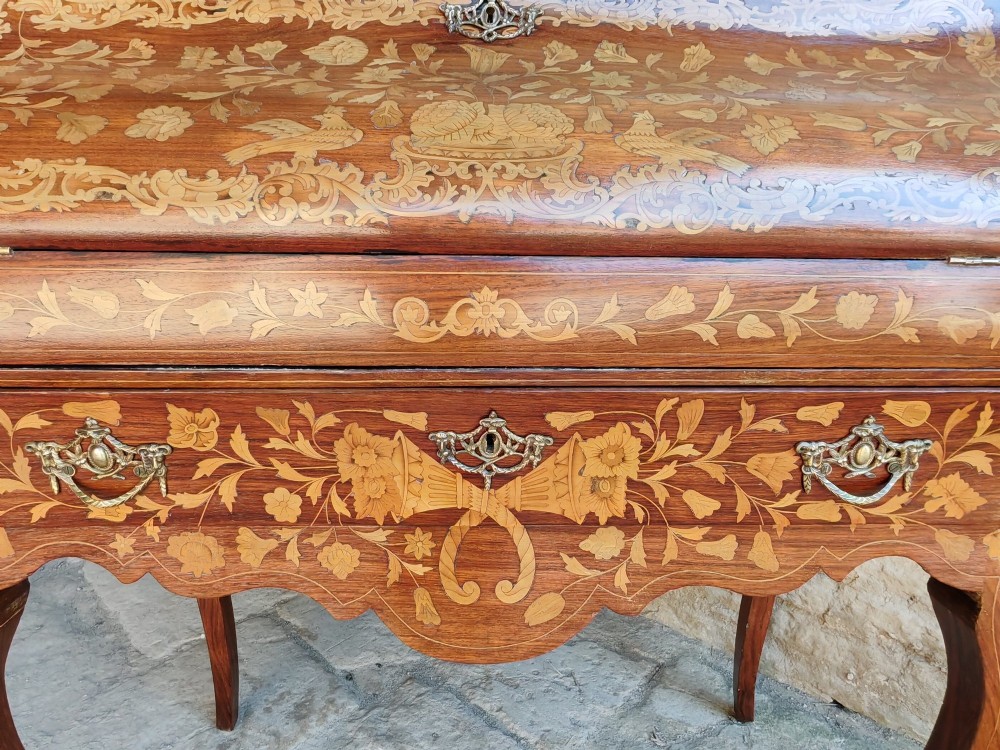 An antique Dutch walnut cylinder bureau decorated with floral marquetry inlays, resting on slender cabriole legs. View III