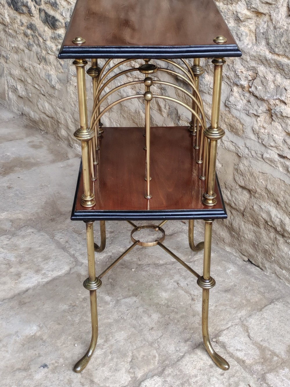 A Regency style two-tier table featuring a polished mahogany top, brass frame with vertical dividers for periodicals, and curved brass legs. View VI