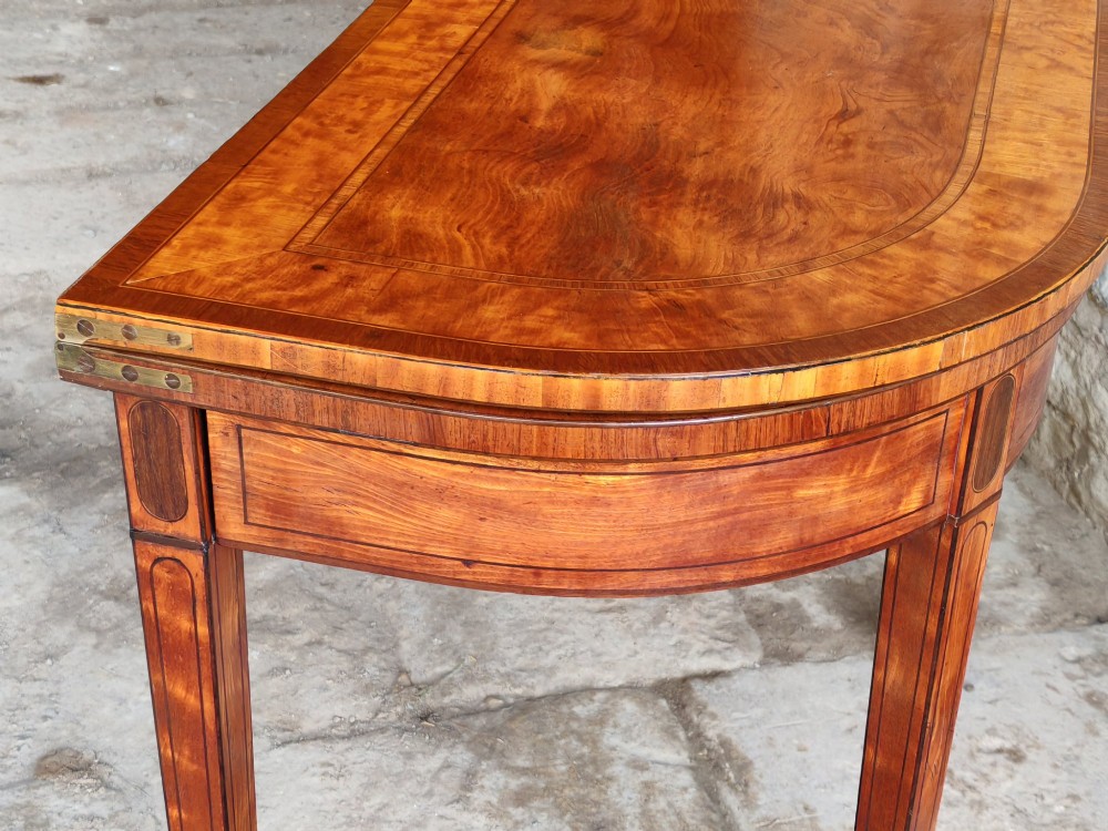 A late 18th-century D-shaped satinwood card table with fine crossbanding, stringing inlay, and square tapered legs. View V