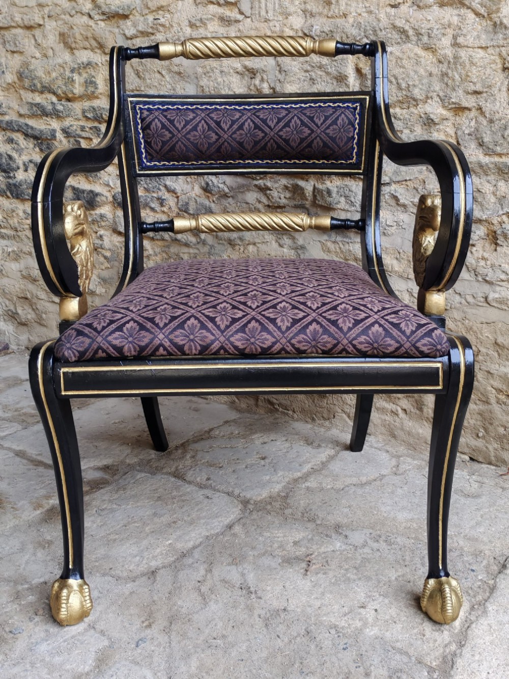 An ebonised and parcel-gilt Regency armchair featuring carved eagle head arm terminals, reeded scroll bars, patterned purple fabric upholstery, and gold paw feet. View III