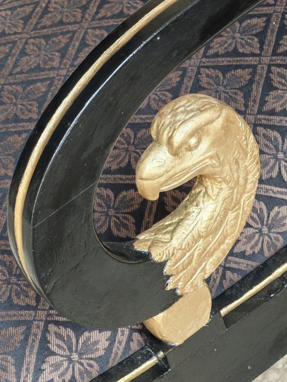 An ebonised and parcel-gilt Regency armchair featuring carved eagle head arm terminals, reeded scroll bars, patterned purple fabric upholstery, and gold paw feet. View VIII