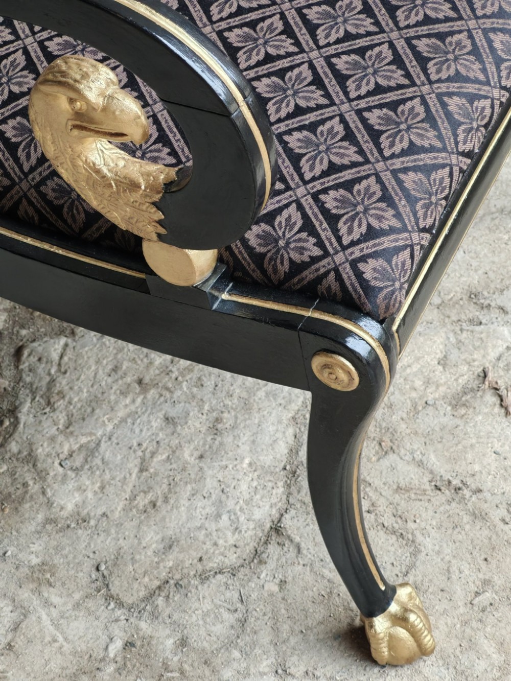 An ebonised and parcel-gilt Regency armchair featuring carved eagle head arm terminals, reeded scroll bars, patterned purple fabric upholstery, and gold paw feet. View IX