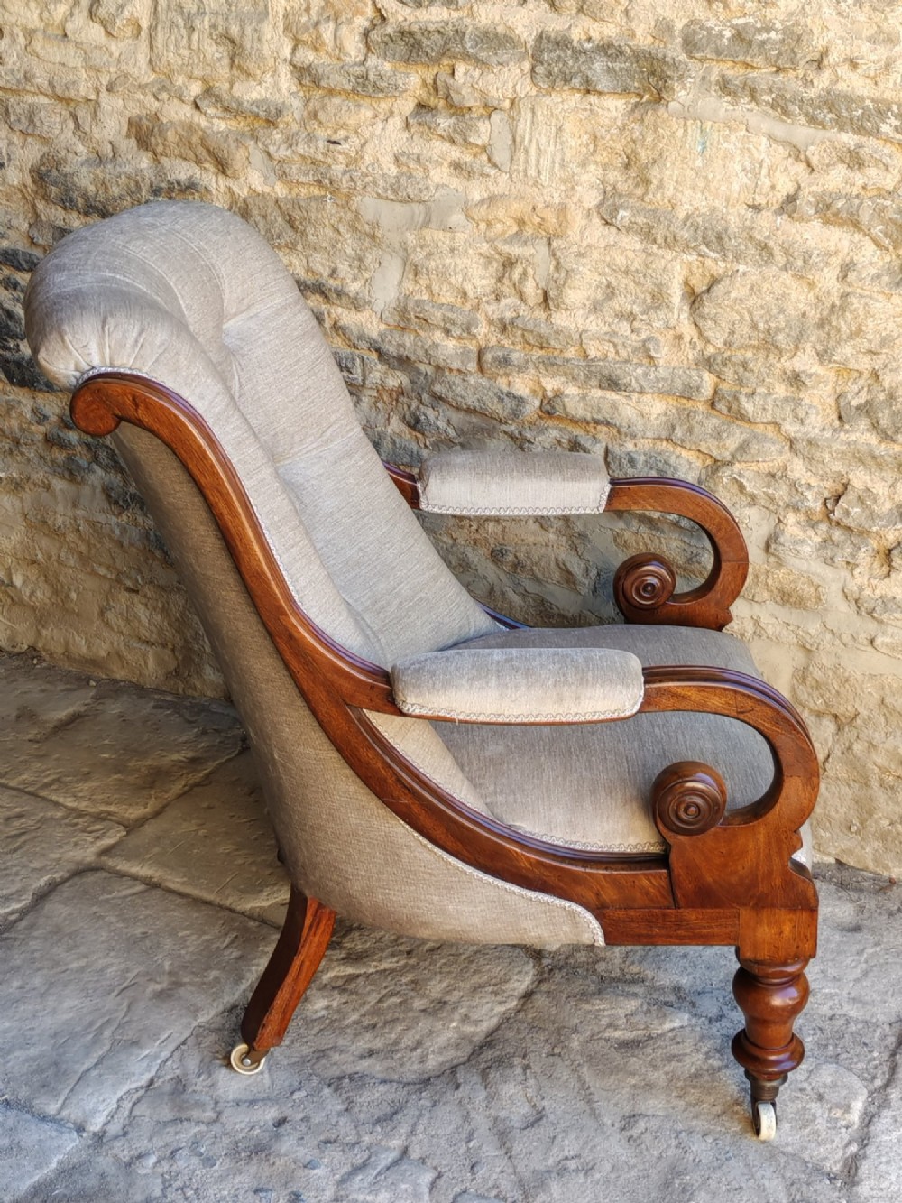 Mid-Victorian walnut armchair featuring light grey button-back upholstery, carved scroll armrests, and turned legs with ceramic casters. View III