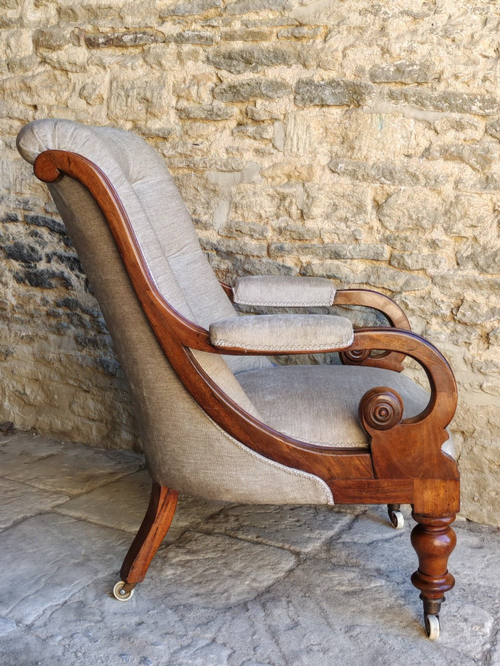 Mid-Victorian walnut armchair featuring light grey button-back upholstery, carved scroll armrests, and turned legs with ceramic casters. View IV