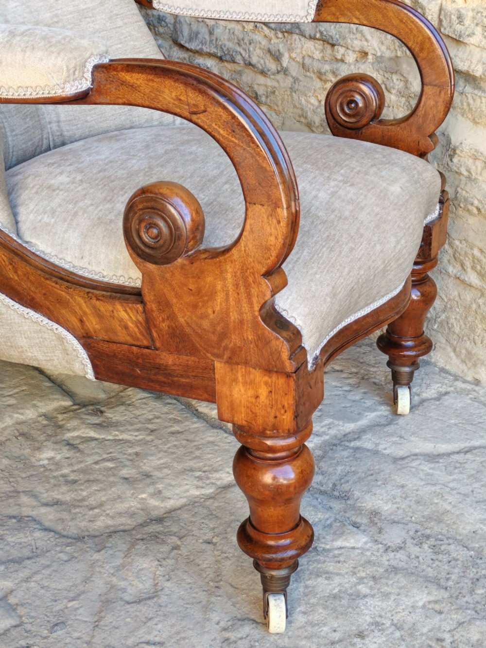Mid-Victorian walnut armchair featuring light grey button-back upholstery, carved scroll armrests, and turned legs with ceramic casters. View V