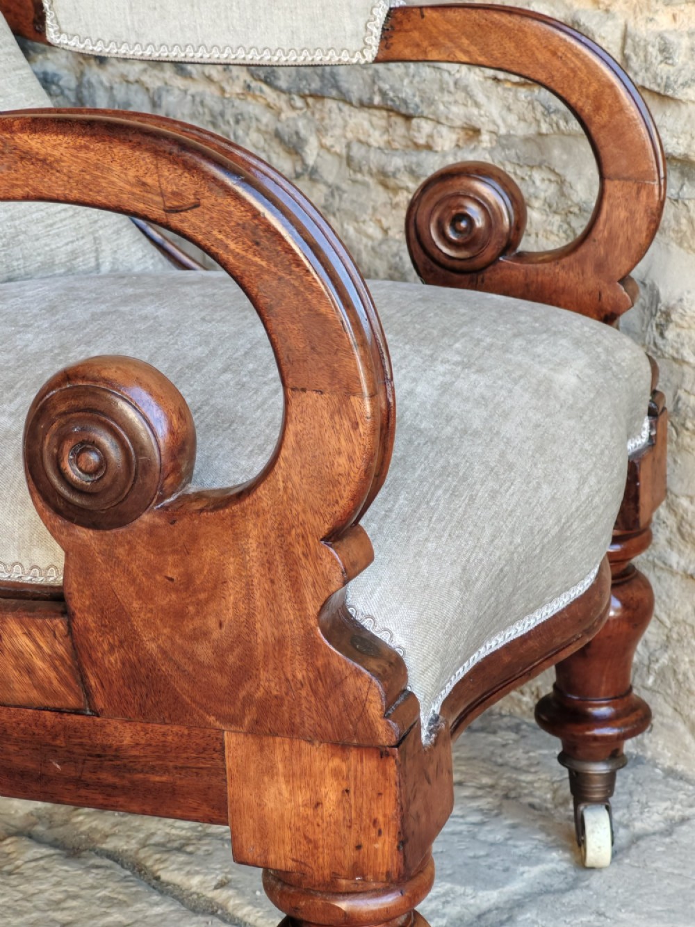 Mid-Victorian walnut armchair featuring light grey button-back upholstery, carved scroll armrests, and turned legs with ceramic casters. View VI