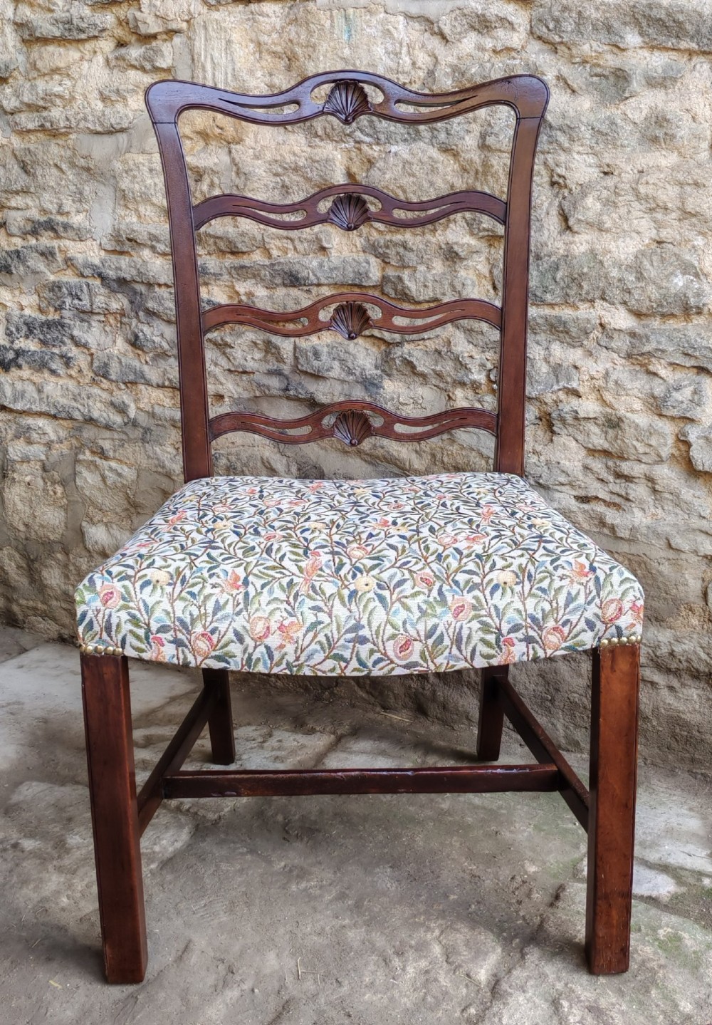 A Victorian mahogany ladderback side chair with pierced shell-carved back rails and a botanical tapestry seat.