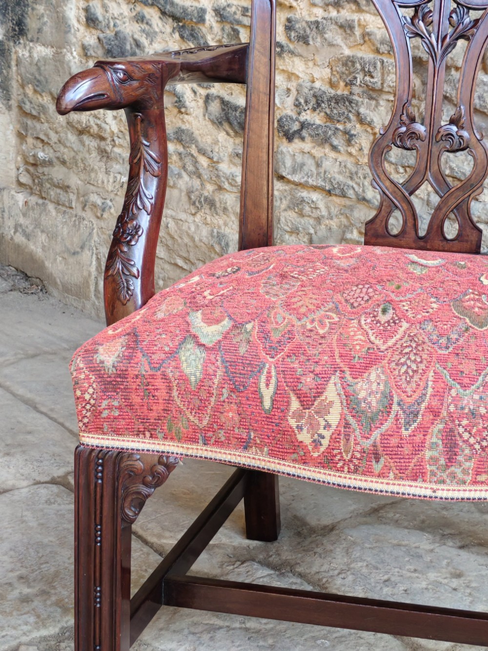 A dark mahogany Chippendale revival carver armchair with an intricately carved splat back and red patterned fabric seat cushion. View V