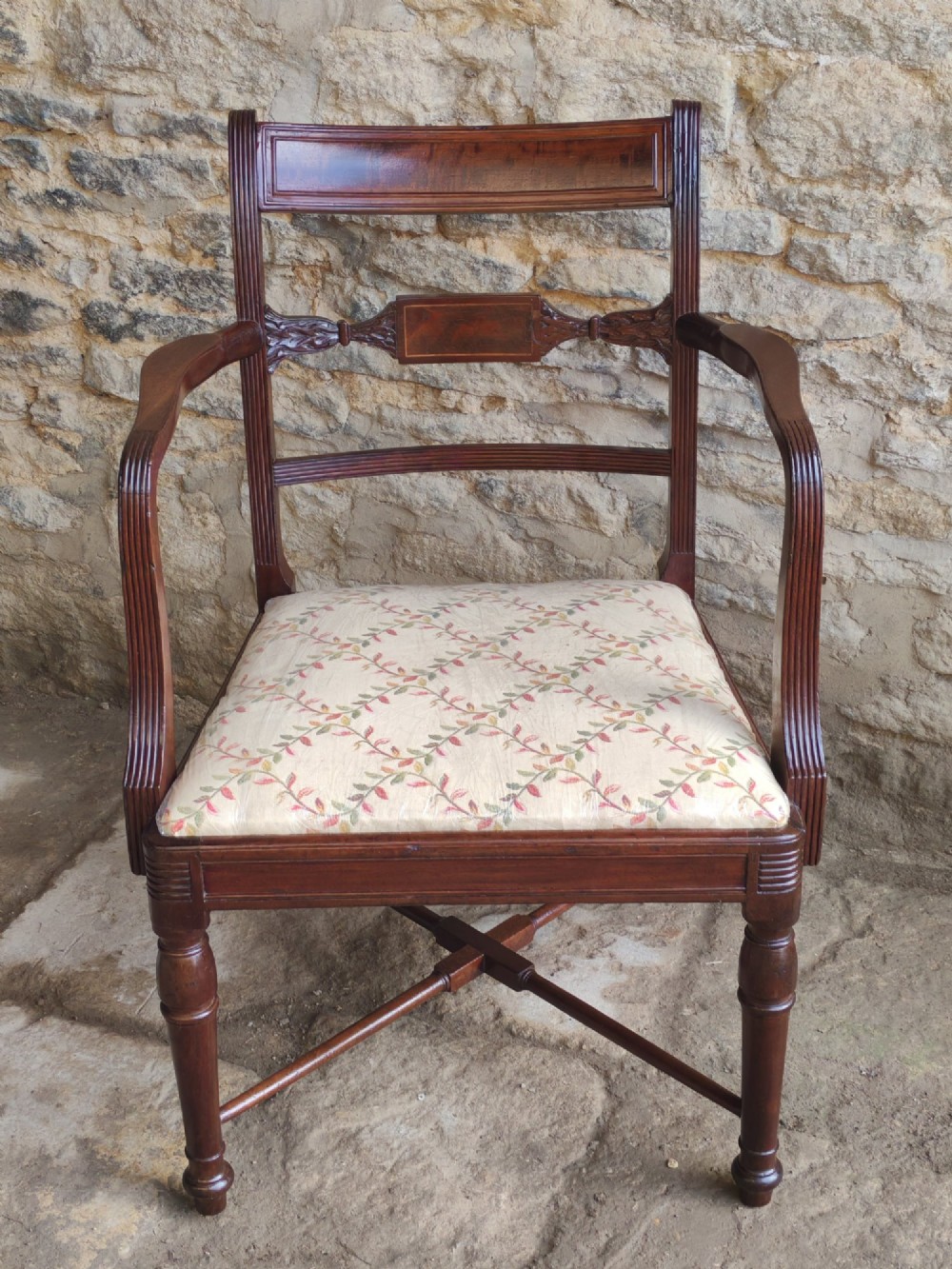 A George III mahogany carver armchair featuring reeded armrests, a carved mid-rail, turned front legs, an X-frame stretcher, and a cream pattern fabric seat. View III