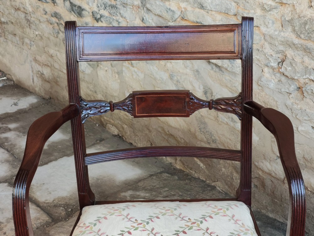 A George III mahogany carver armchair featuring reeded armrests, a carved mid-rail, turned front legs, an X-frame stretcher, and a cream pattern fabric seat. View IV